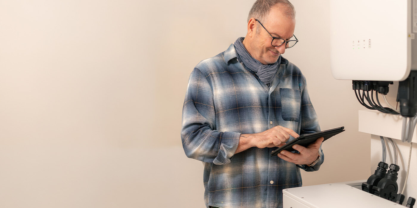 Ein FENECON Techniker prüft ein Speichersystem mit einem Tablet